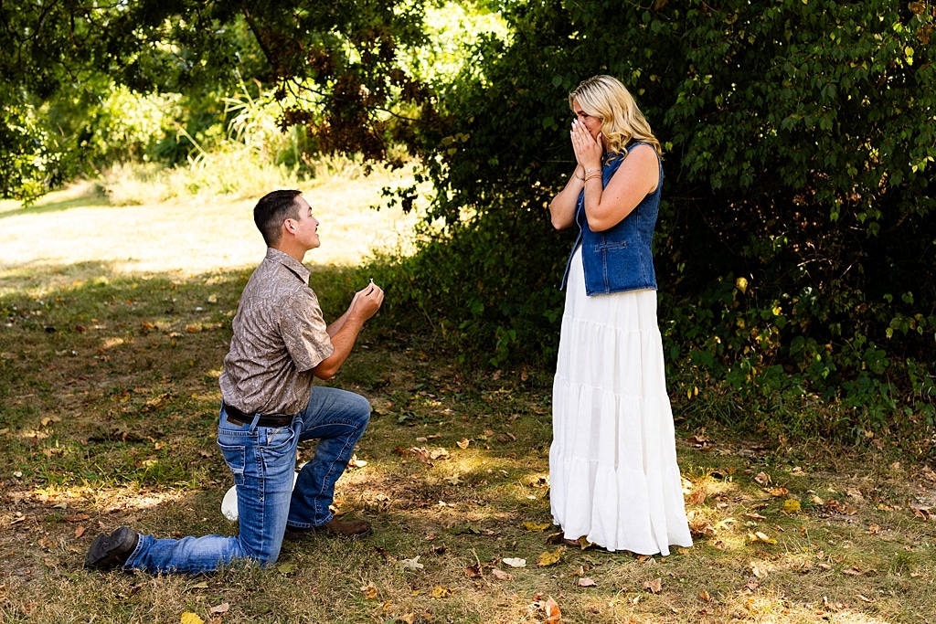Tyler proposing to Rachel at Chandler Hill Vineyards in Defiance Missouri
Couple standing back to back moments before the surprise proposal
Rachel crying with joy as Tyler kneels during the proposal
Newly engaged couple hugging surrounded by vineyard scenery
Close up of engagement ring in front of rolling vineyard hills